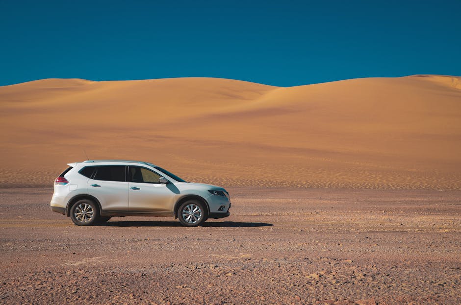 A white SUV drives through a vast desert landscape under a clear blue sky, showcasing adventure and exploration.