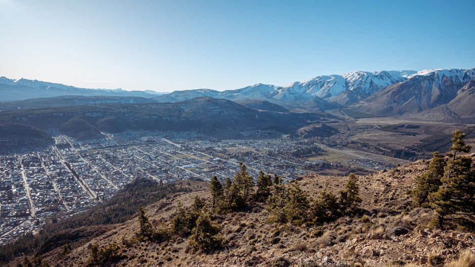 A breathtaking panoramic view of Esquel, Argentina, with snow-capped mountains and clear blue skies.