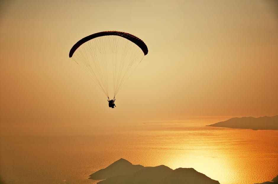 A silhouette of a paraglider flying over the stunning Ölüdeniz at sunset